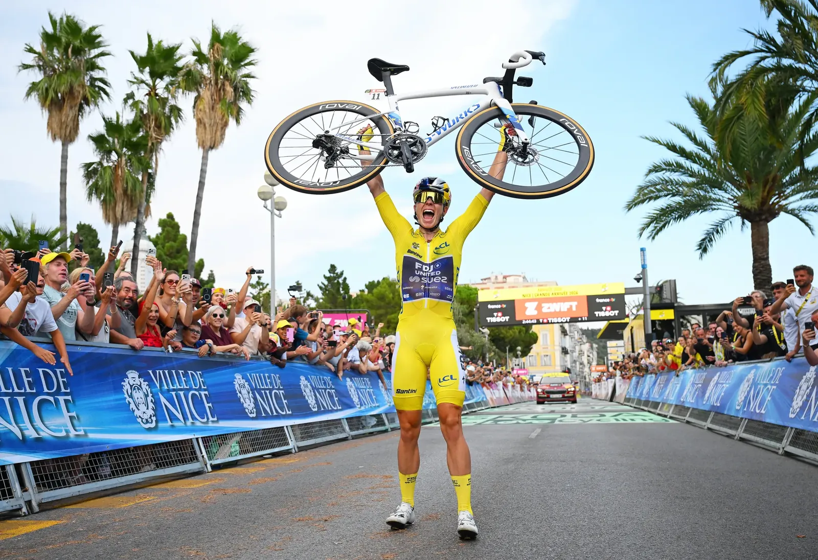 Demi Vollering tilt juichend haar fiets boven haar hoofd nadat ze solo de slotrit heeft gewonnen in Nice en de eindzege in de Tour heeft veiliggesteld.Foto Tim de Waele/Getty Images