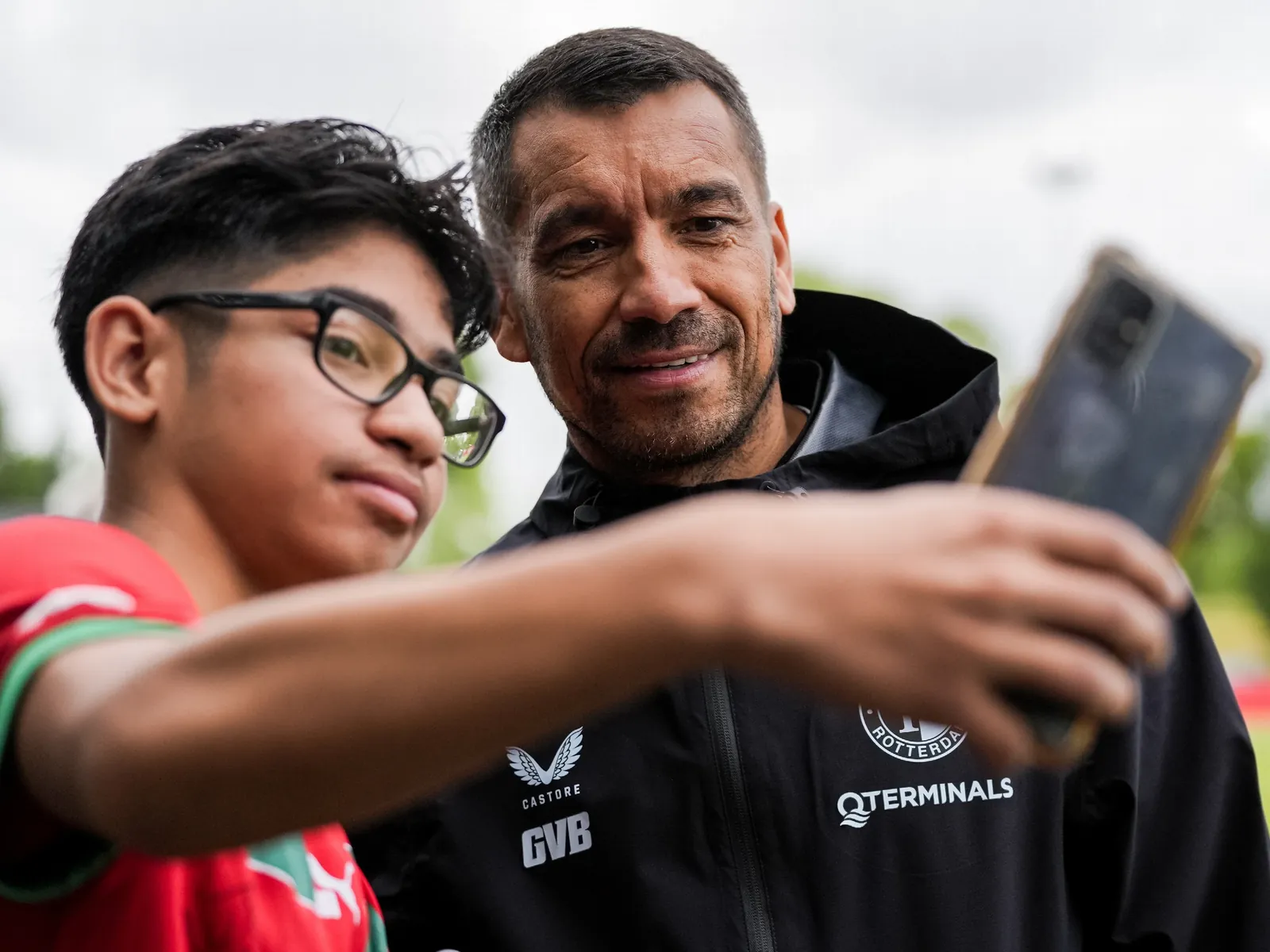 Een jonge Feyenoord-fan maakt een selfie met Feyenoord-trainer Giovanni van Bronckhorst